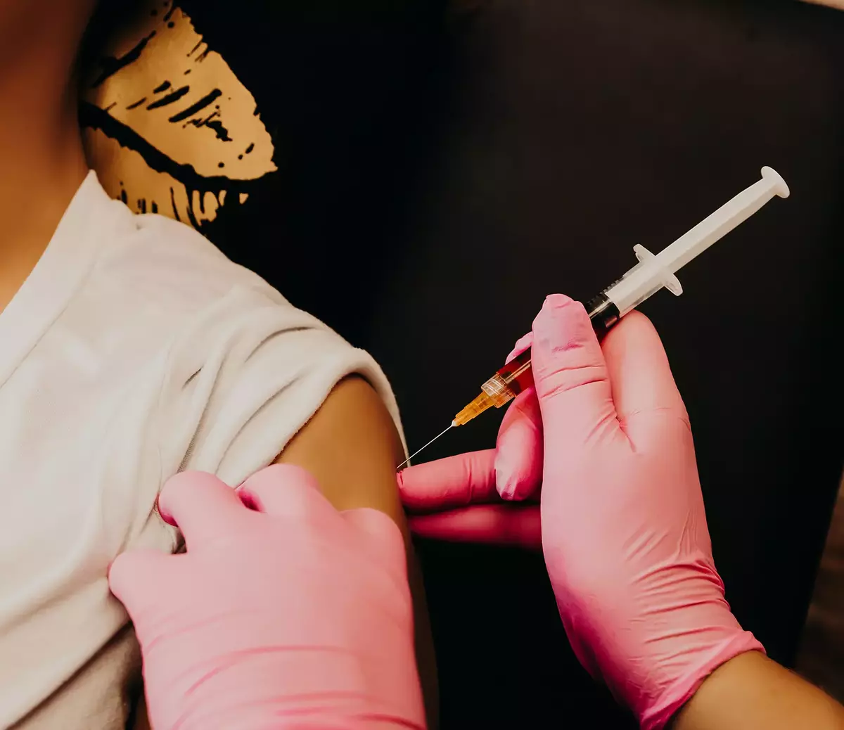 health worker drawing vaccine in vial into syringe 